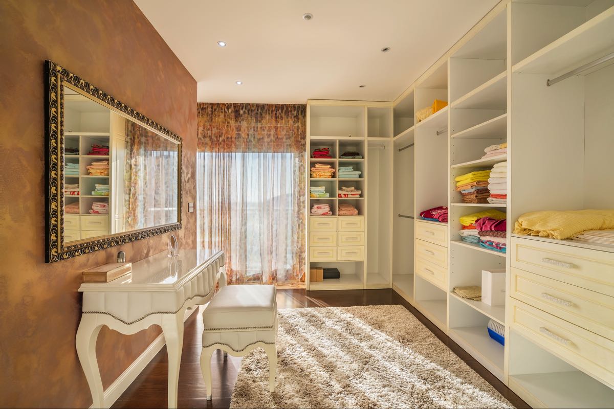 Spacious walk-in closet with white furniture and a vanity table in a villa in Budva, Montenegro.