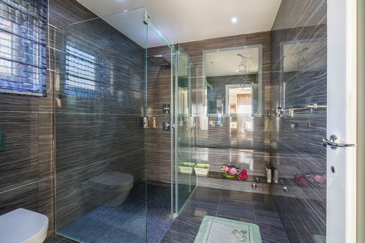 Modern bathroom with a shower cabin and dark porcelain tile finishes in a villa in Budva, Montenegro.