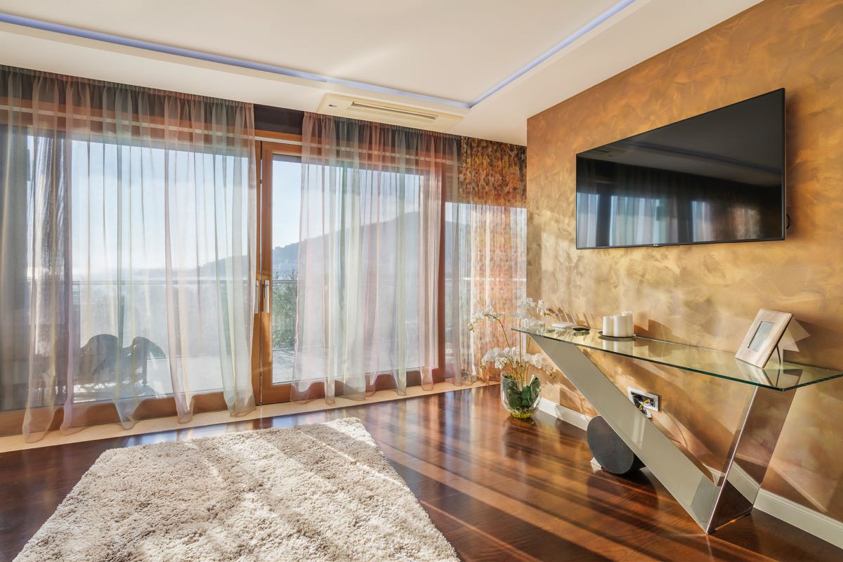 Villa living room in Budva, Montenegro: panoramic windows, glass console, wall-mounted TV with decorative finish.
