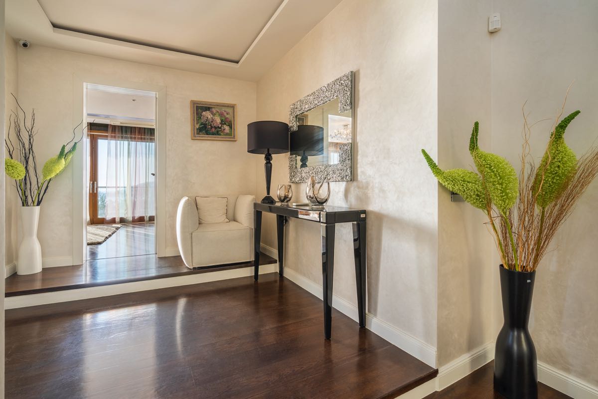 Bright villa hallway in Budva, Montenegro: dark parquet flooring, a console table, mirror, and stylish interior decor.