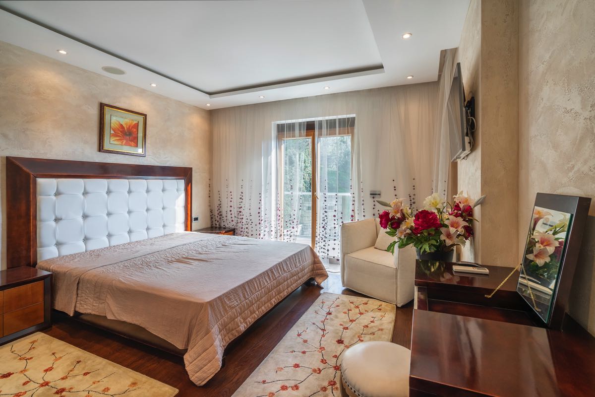Cozy bedroom with a double bed in a villa in Budva, Montenegro: stylish interior, light finishes, and a balcony.