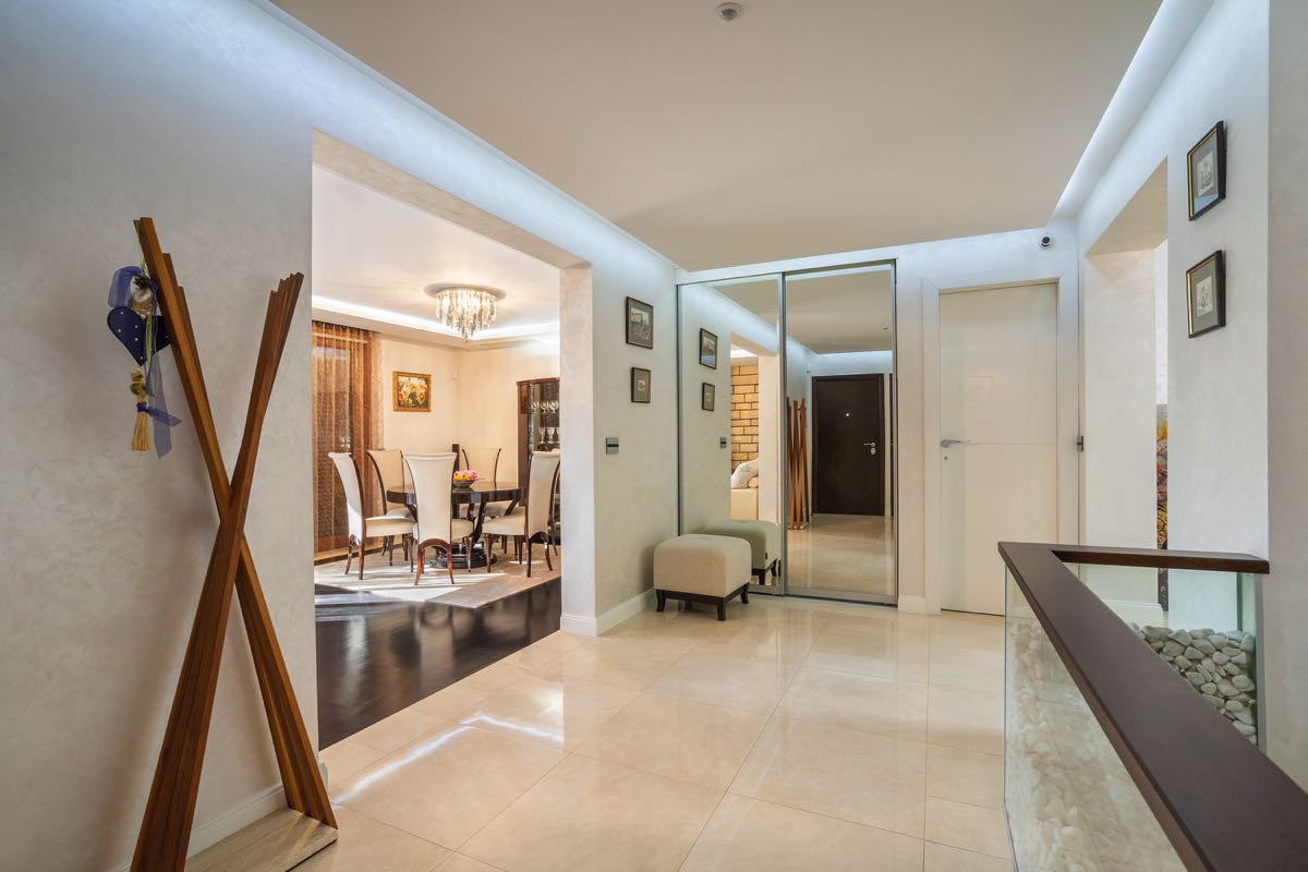 Bright hallway and dining area in a villa in Budva, Montenegro: mirrored wardrobe, marble floor, and stylish furniture.