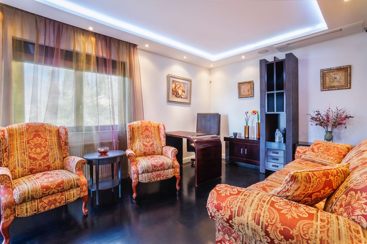 Living room with classic furniture and dark parquet flooring in a villa in Budva, Montenegro: a cozy interior with bright upholstery.