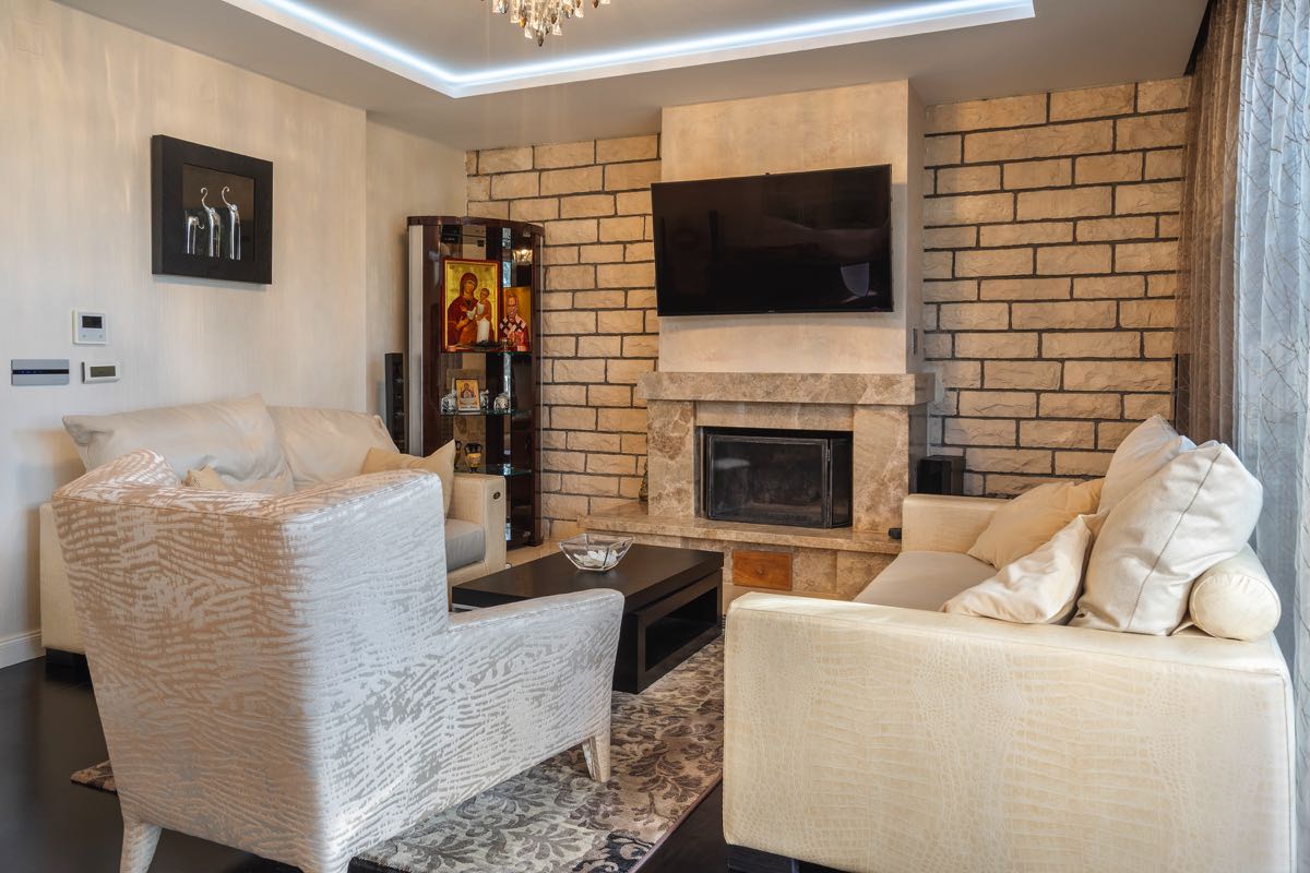 Living room with a fireplace and soft seating in a villa interior in Budva, Montenegro. Stone finishes and modern design.