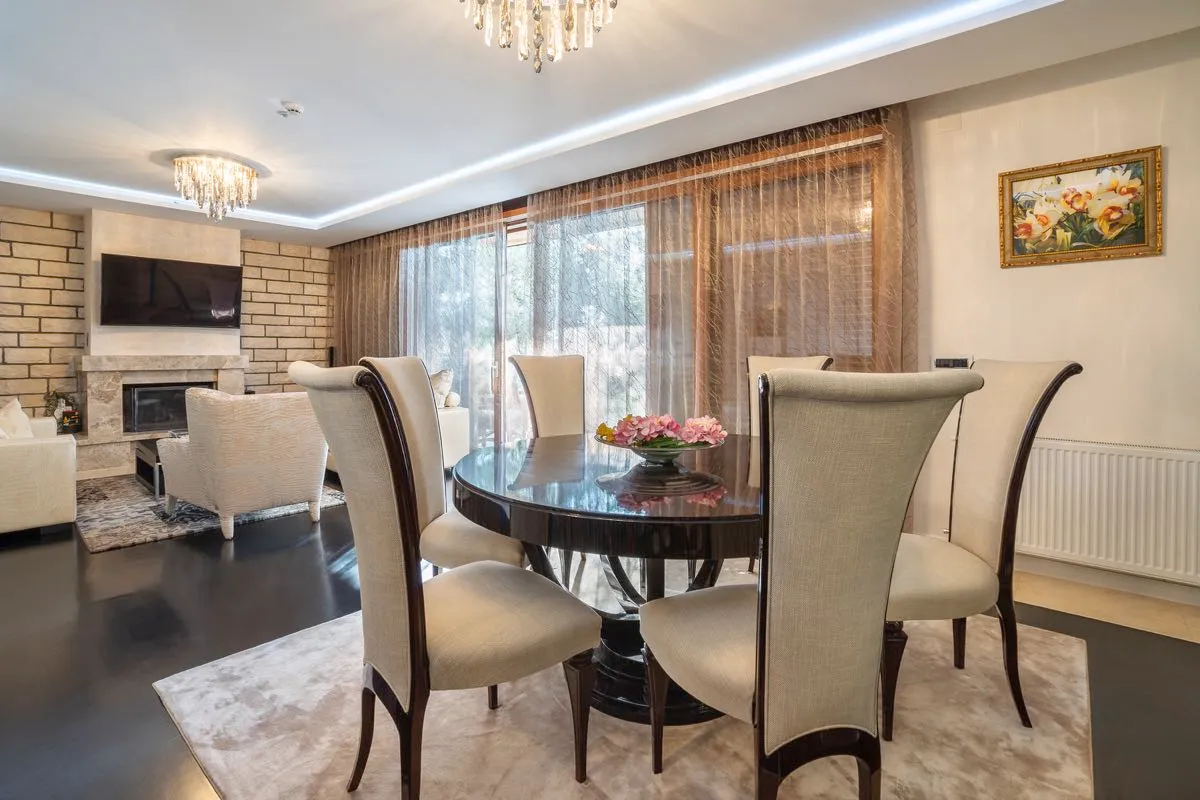 Living room with dining area, fireplace, sofa, and crystal chandeliers.