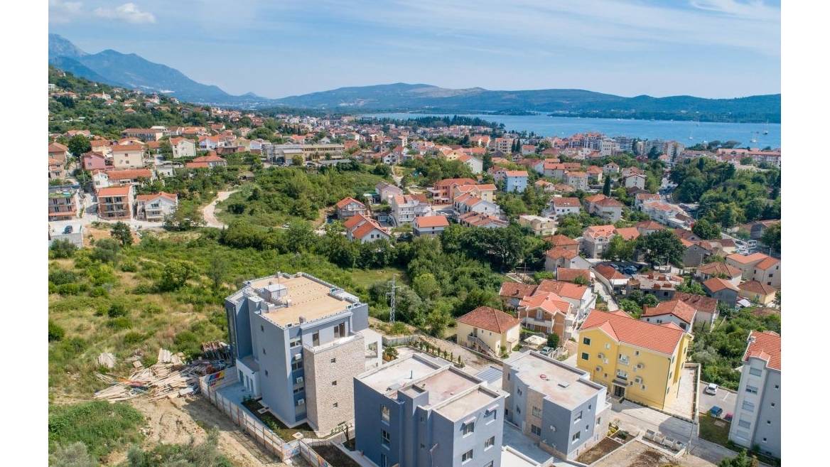 Panoramic view of a residential complex in Tivat, Montenegro: modern buildings with terraces and a sea view against a mountain backdrop.