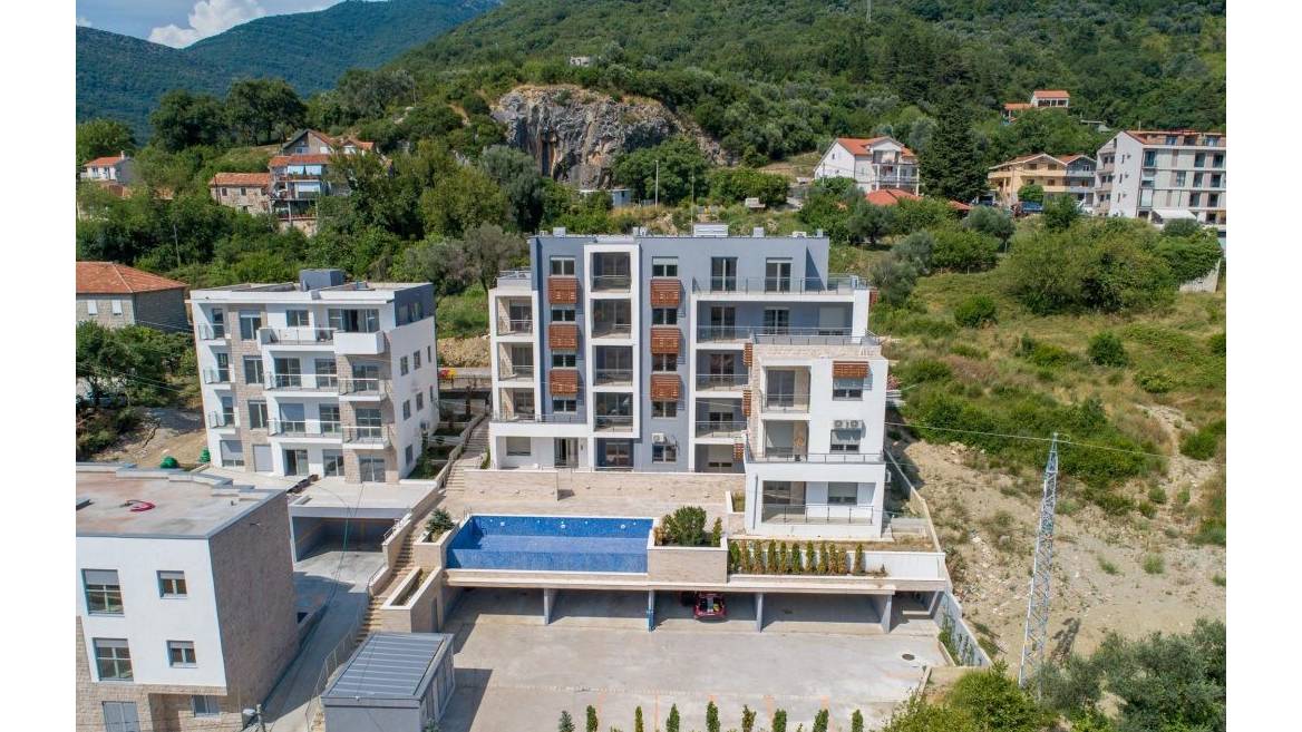 Modern residential complex with a pool and parking in Tivat, Montenegro: top view of the building with panoramic windows.