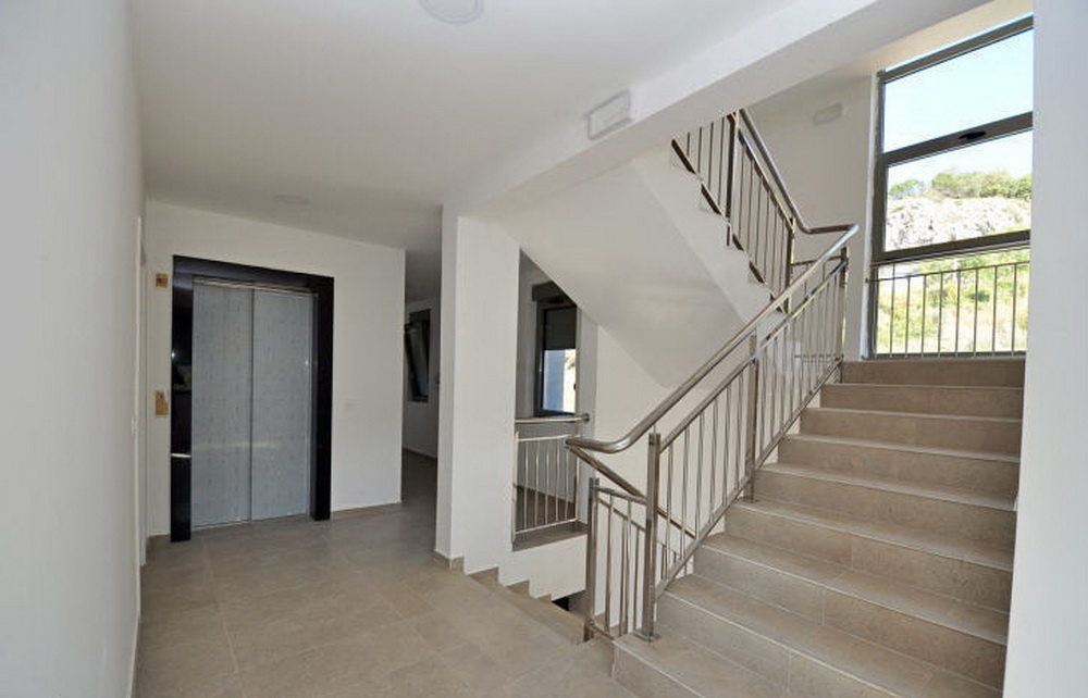 Modern entrance hall with elevator and staircase in a residential complex in Tivat, Montenegro: bright interior and panoramic windows.