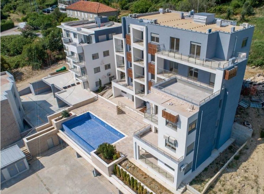Modern residential complex in Tivat, Montenegro, with an outdoor pool, terraces, and landscaped grounds.
