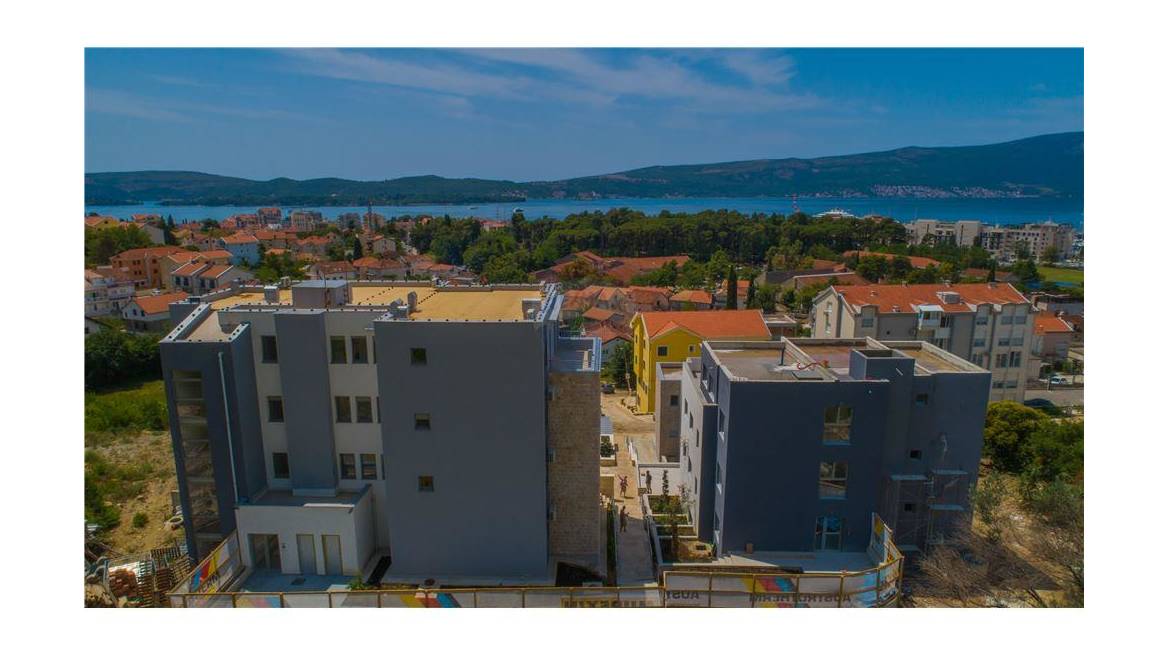 Aerial view of a modern residential complex in Tivat, Montenegro, with panoramic views of the sea and cityscape.