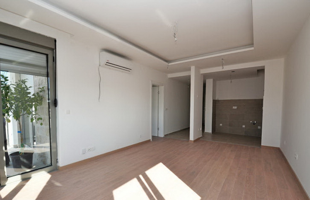 Bright living room with laminate flooring and air conditioning in a new residential complex in Tivat, Montenegro, with a view of the terrace.