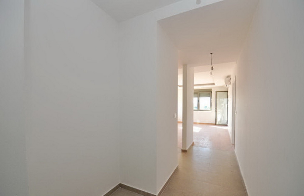 Bright hallway and living room in a new building in Tivat, Montenegro: finished interior, tiled floor, window view.