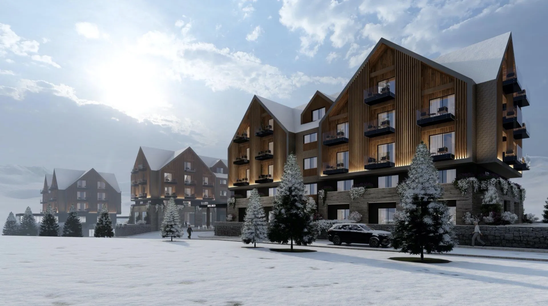 Exterior view of a modern mountain hotel with wood facade and balconies in a snowy winter landscape.