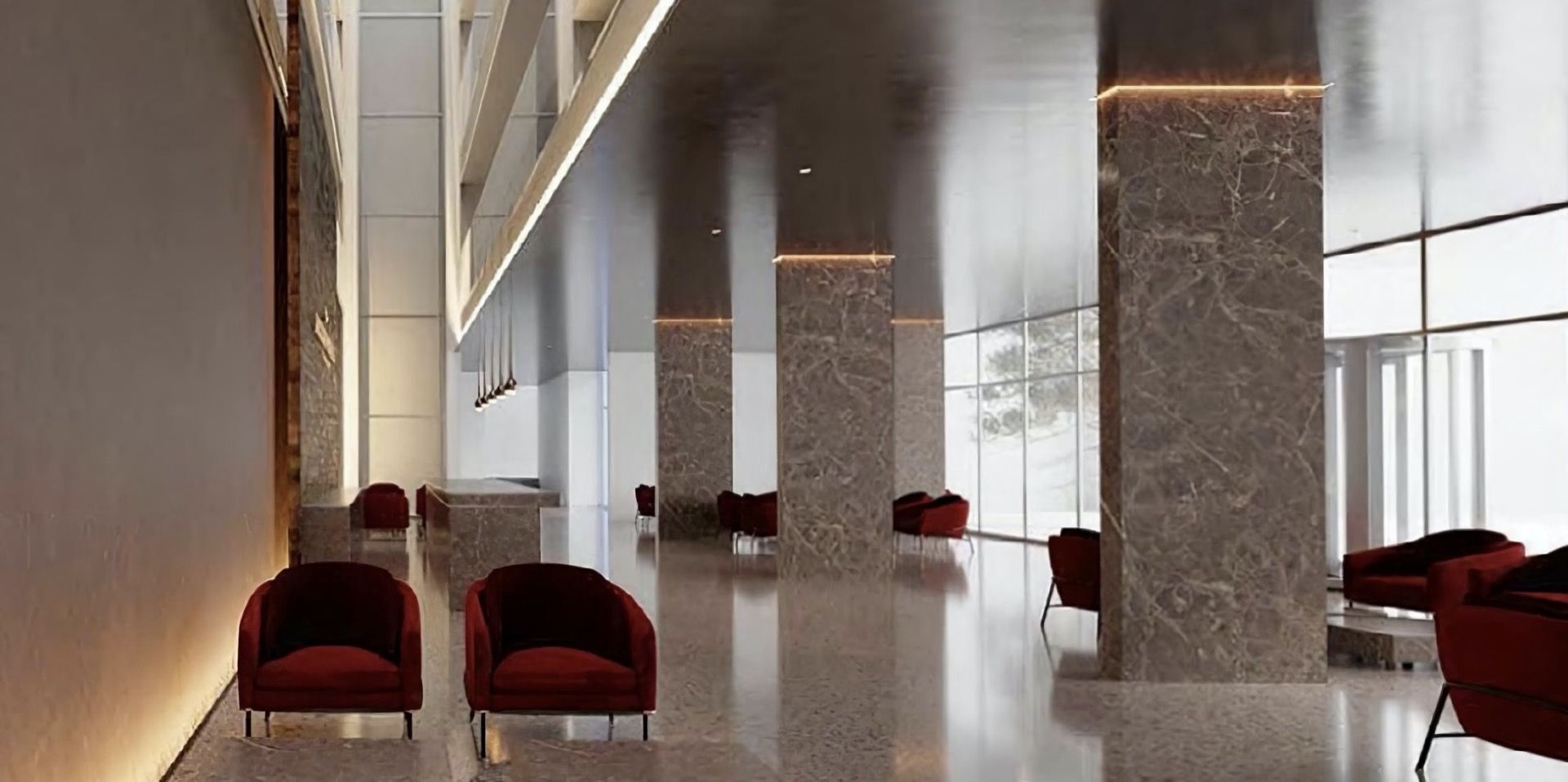 Hotel lobby interior in Kolašin, Montenegro: marble columns, red armchairs, and panoramic windows in a modern style.