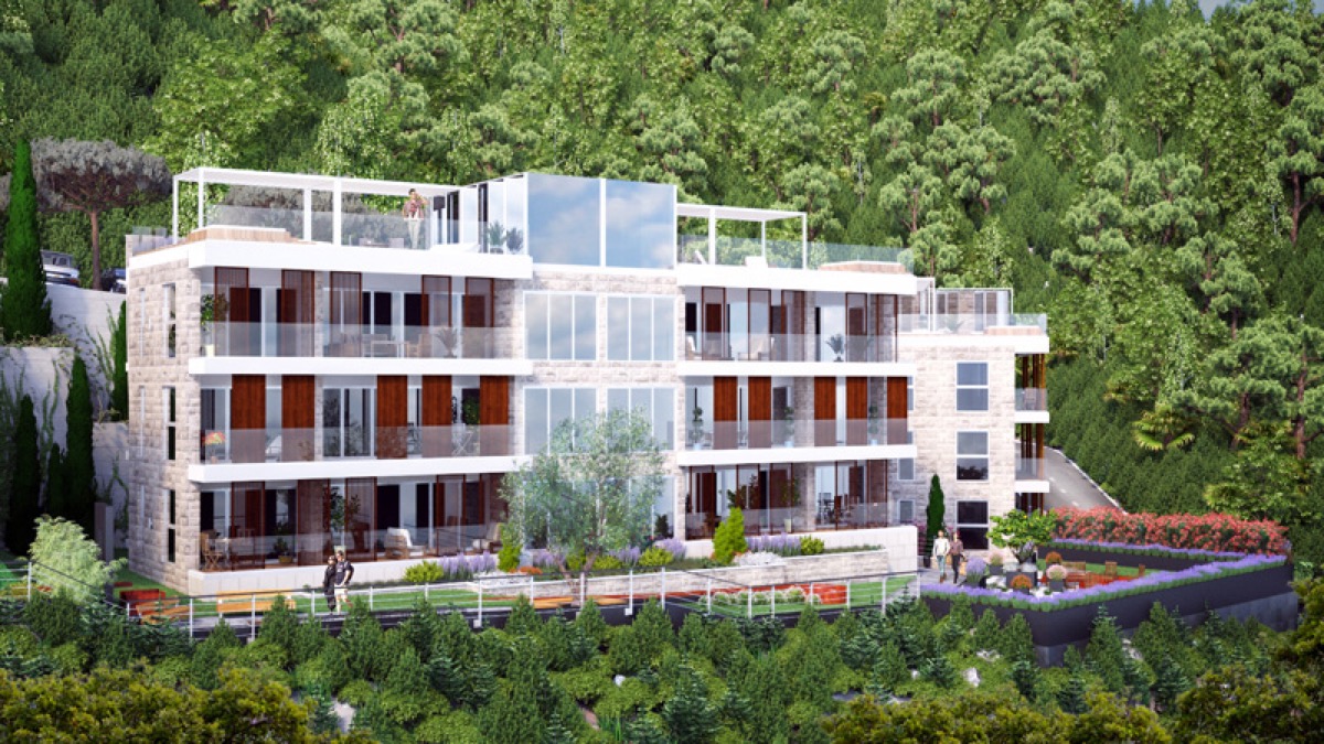 Modern residential complex in Budva, Montenegro: facade with panoramic windows, terraces, and a view of the forested area.