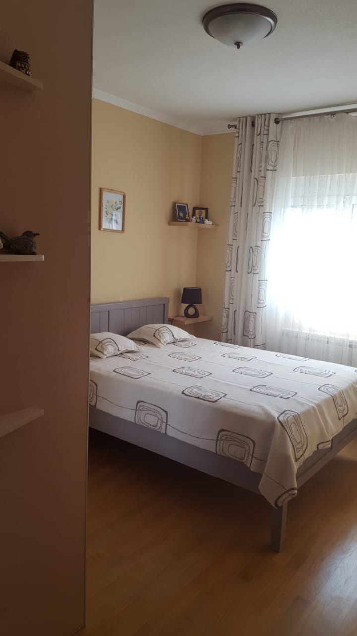 Cozy bedroom with a double bed in a house in Shushan, Montenegro: light finishes, parquet flooring, and patterned curtains.