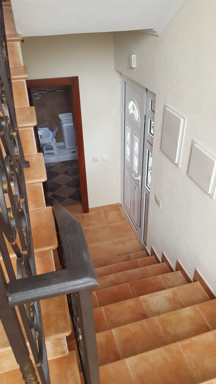 Staircase with wrought-iron railings and the front door in a house in Shushan, Montenegro, view of the hallway and bathroom.
