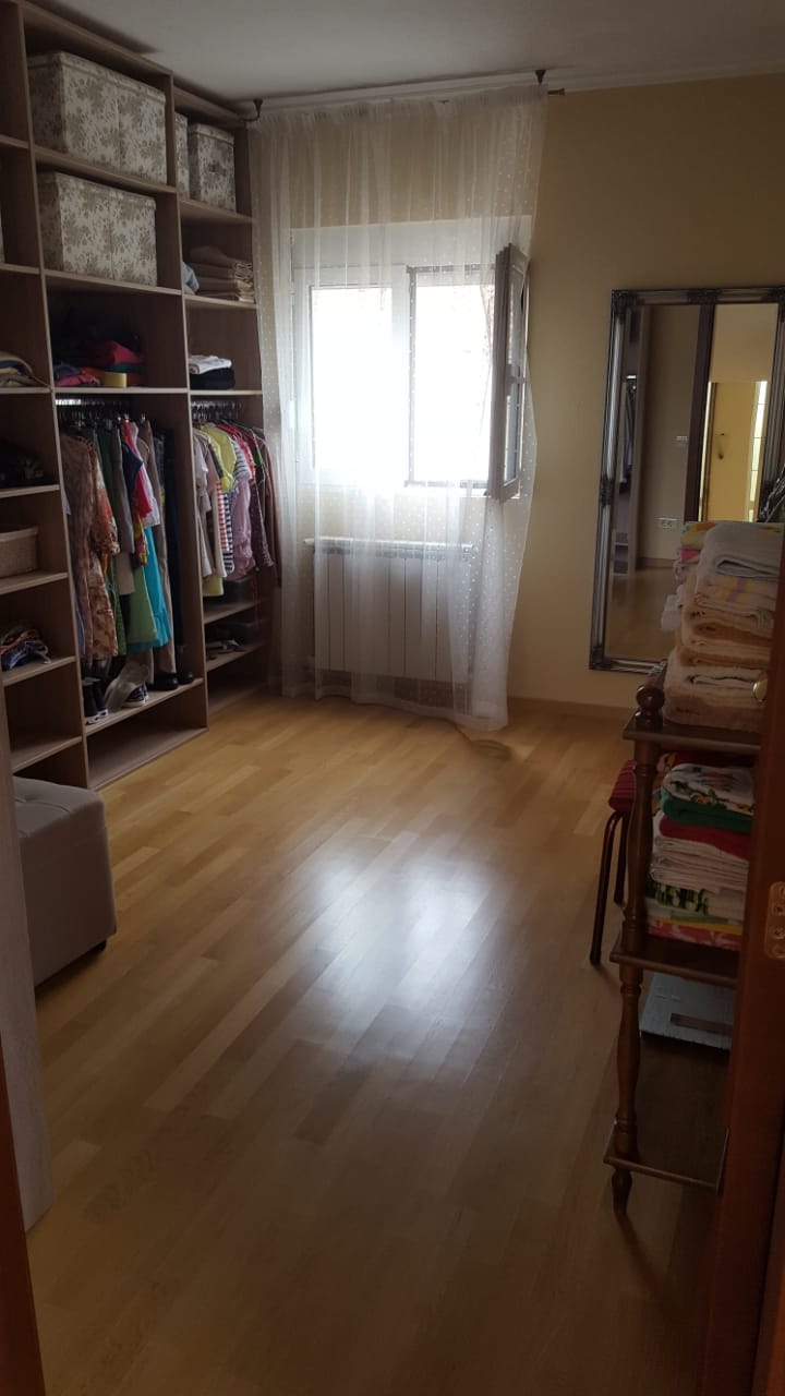 Walk-in closet with open shelving and a mirror in a house, Shushan, Montenegro. Bright room with parquet flooring.