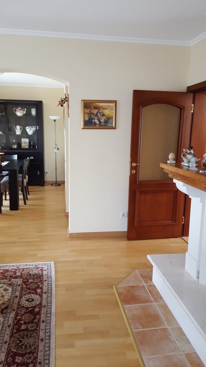 Living room interior with a fireplace and dining area in a house, Shushan, Montenegro: parquet flooring, wooden doors, and classic decor.