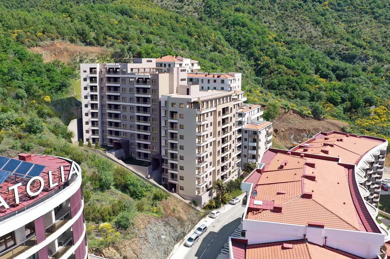 Aerial view of a residential complex in Bečići, Montenegro: modern multi-story buildings with terraces on a mountainside.