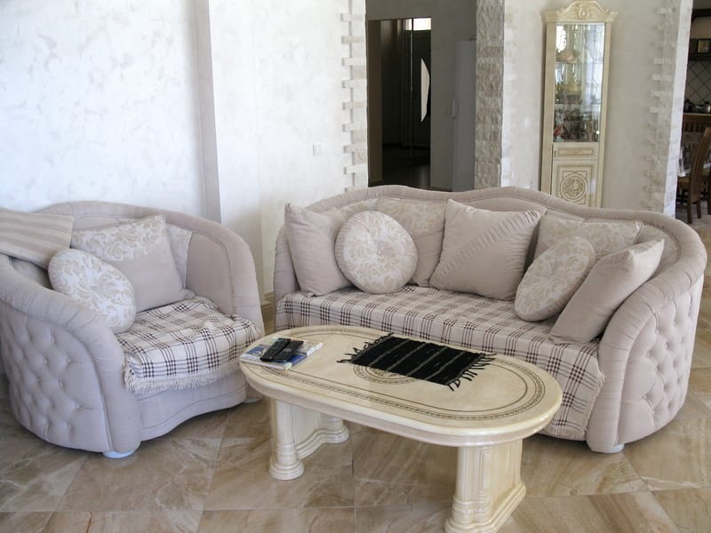 Living room in a villa in Shushan, Montenegro: light upholstered furniture, classic interior, and stone finishes.