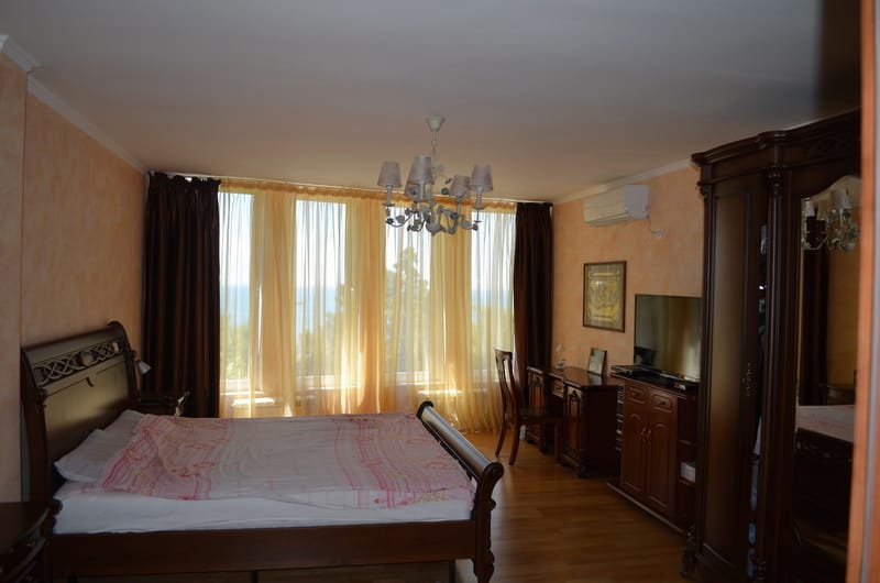 Bedroom with classic dark wood furniture and sea view in a villa in Šušanj, Montenegro.
