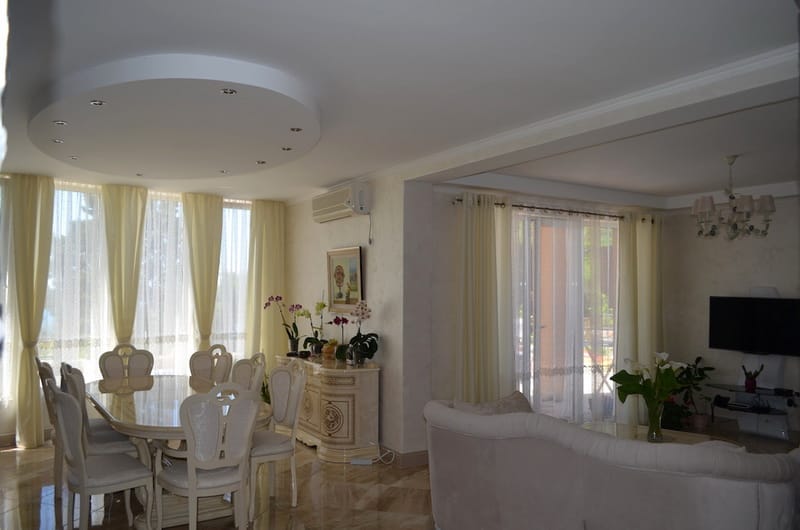 Spacious living room with dining area and light-colored furniture in a villa in Shushan, Montenegro, with access to the terrace.