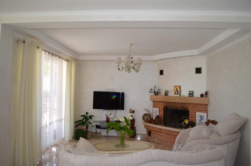 Living room with a fireplace and upholstered furniture in the interior of a villa in Shushan, Montenegro. Bright design, panoramic window.