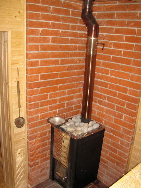 Harvia stove with stones in the villa sauna in Shushan, Montenegro, with red brick and light wood wall finish.