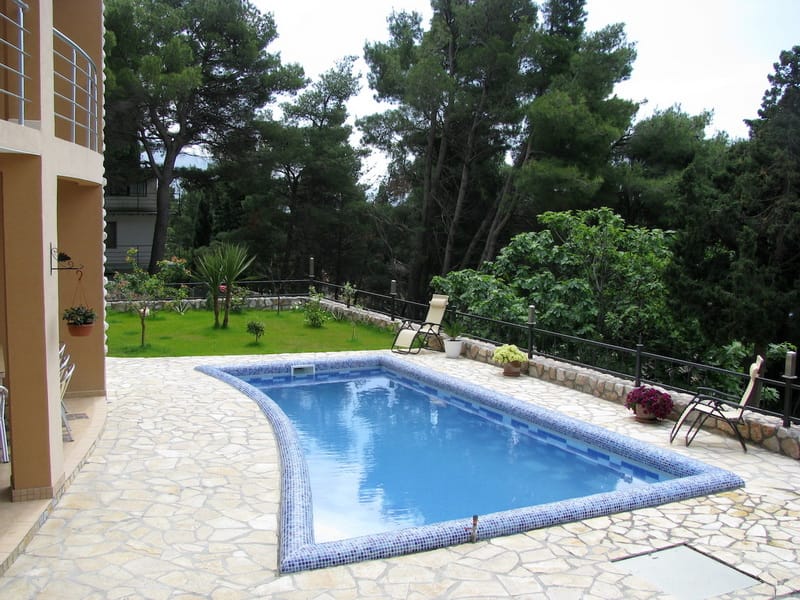Private pool at a villa in Shushan, Montenegro: a stone-finished terrace, sun loungers, and a green garden around it.