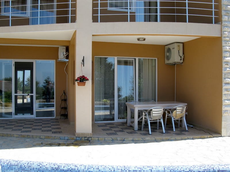 Villa terrace in Shushan, Montenegro: dining area with table and chairs, panoramic windows, and a view of the pool.