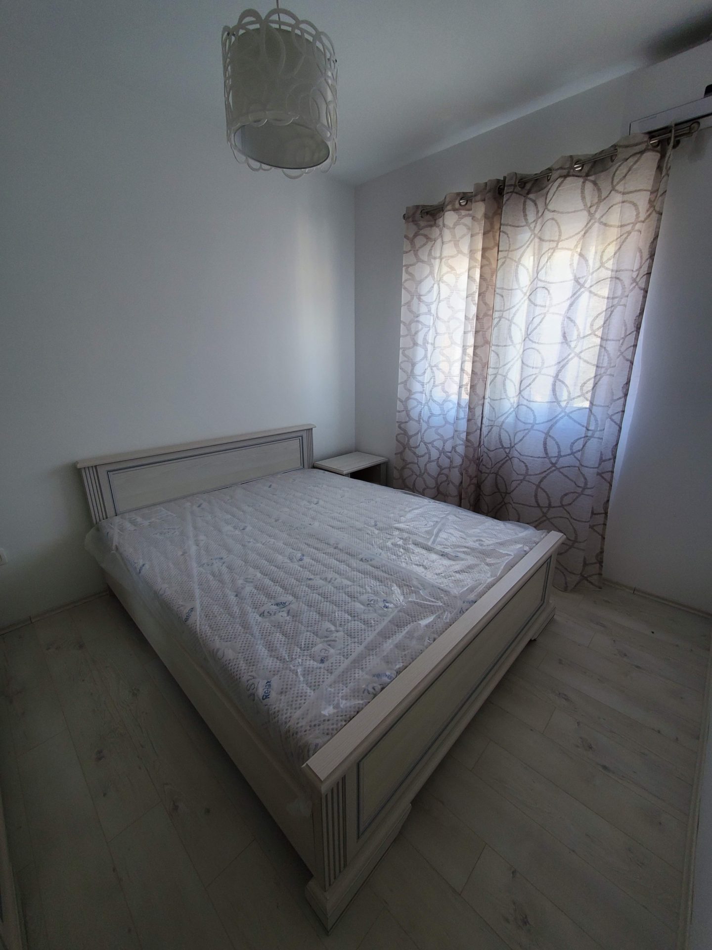 Bright bedroom with a double bed in an apartment in Budva, Montenegro: laminate flooring, new furniture, and curtains on the windows.