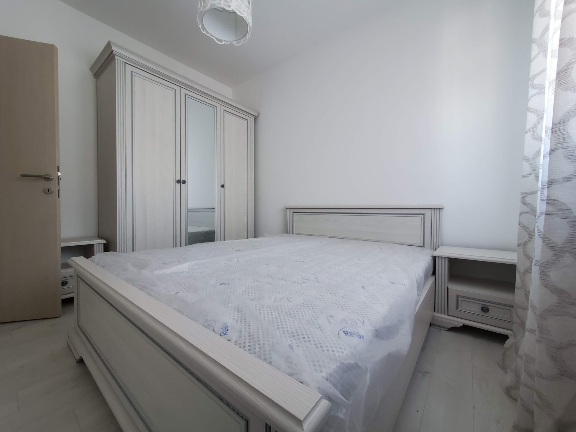 Bright bedroom in an apartment in Budva, Montenegro: a double bed, a mirrored wardrobe, and bedside tables.