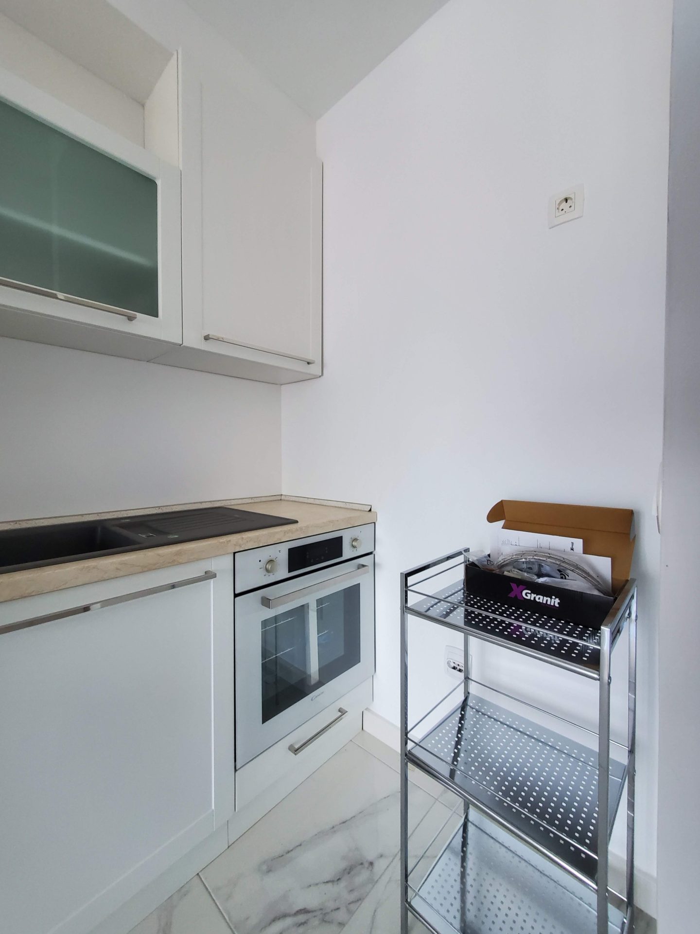 Modern white kitchen with built-in appliances in an apartment, Budva, Montenegro. Compact kitchen set with sink.