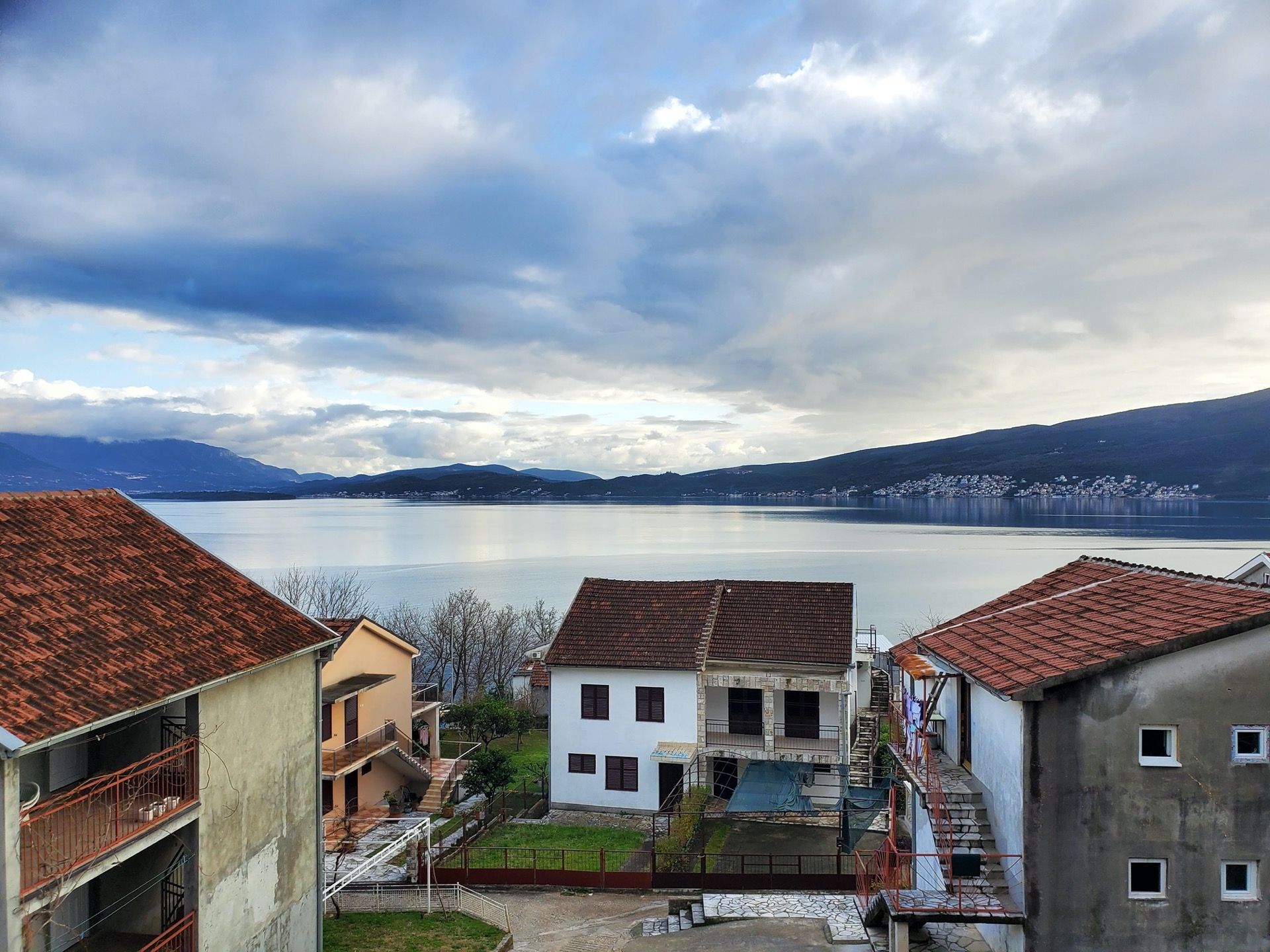 Sea and mountain view from a hotel in Bijela, Montenegro: private houses with tiled roofs and a panoramic seascape.