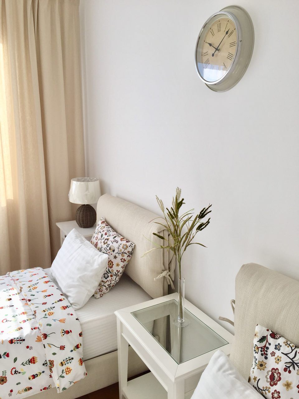 Cozy bedroom in an apartment in Morinj, Montenegro: two beds with beige headboards, a bright interior, and a wall clock.
