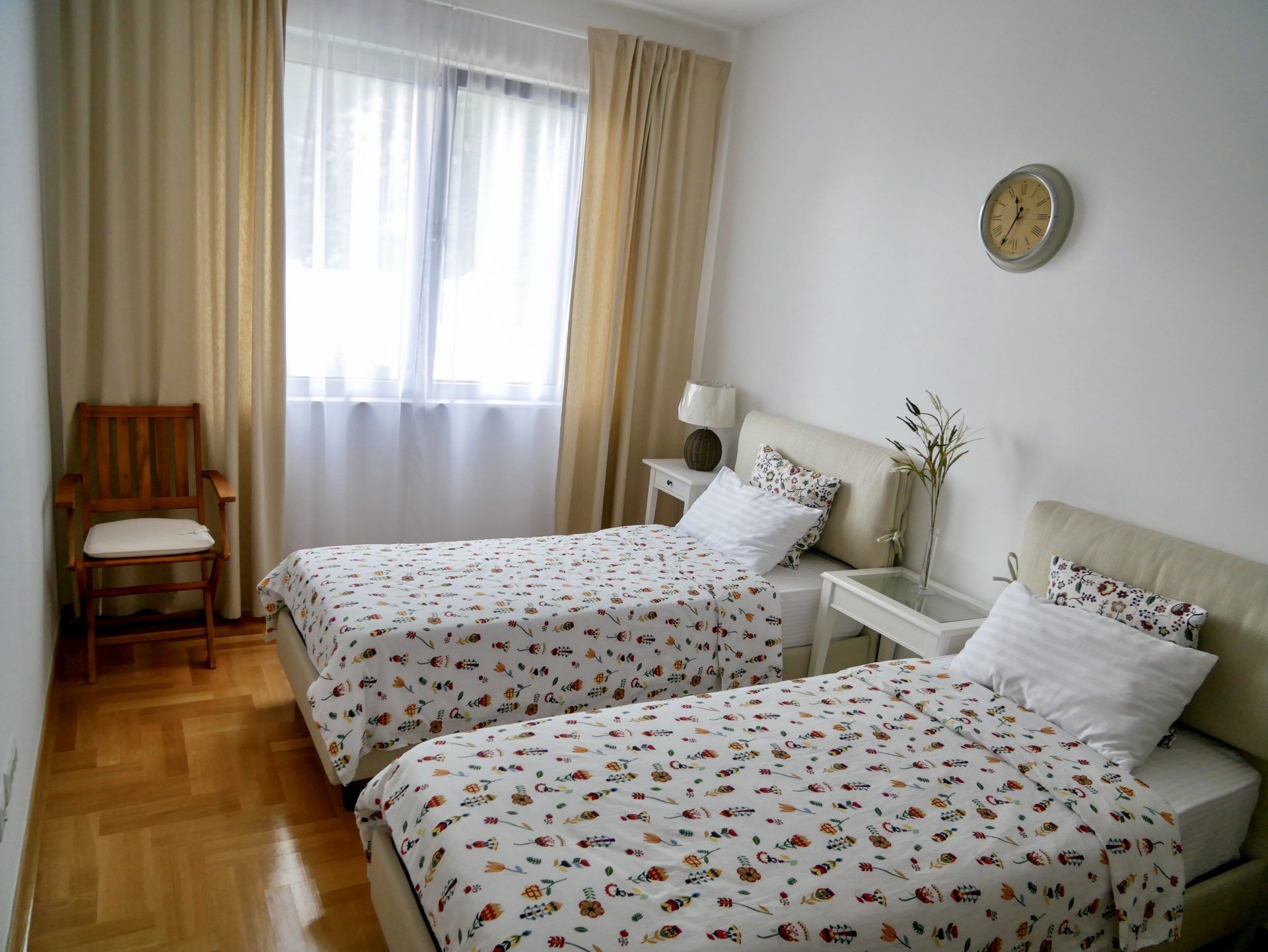 Bright bedroom with two beds in an apartment in Morinj, Montenegro: parquet flooring, white walls, and a cozy interior.