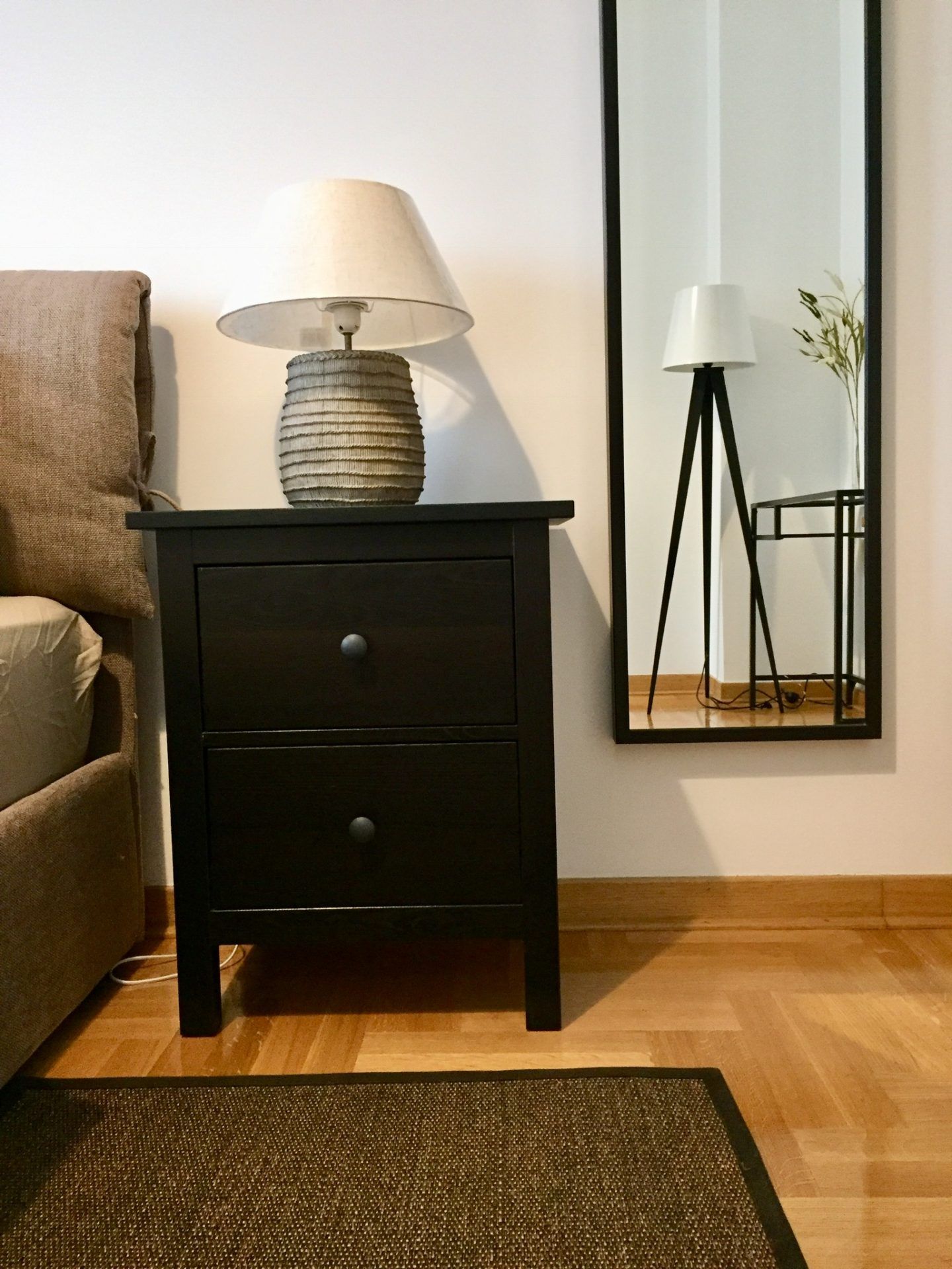 Bedroom interior in an apartment in Morinj, Montenegro: black bedside table, table lamp, and wall mirror.