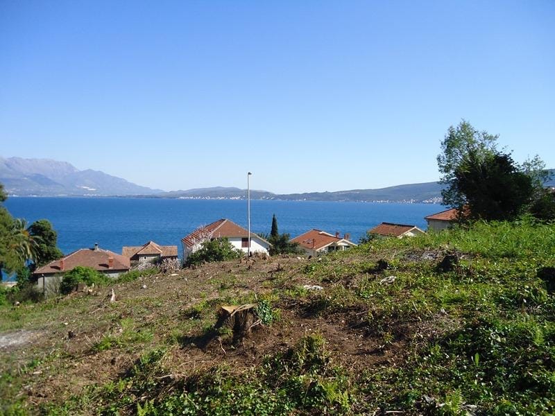 Building plot in Bijela, Montenegro, with panoramic sea and mountain views on a sunny day.