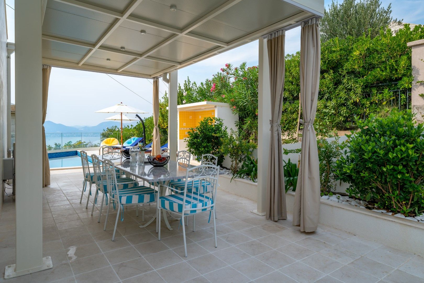 House terrace in Blizikuće, Montenegro: dining area, pool and sea view, modern garden furniture.