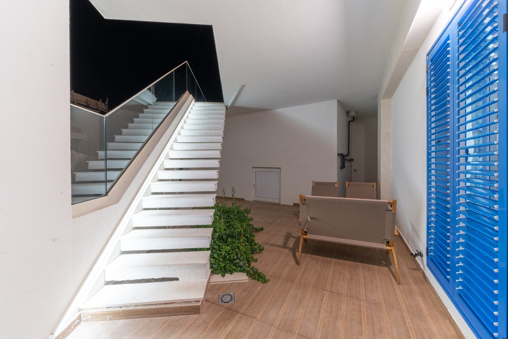 House terrace in Blizikuće, Montenegro: modern staircase with glass railing, garden furniture, and blue shutters.