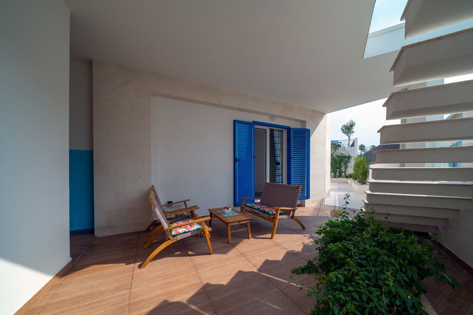 Cozy terrace with wooden furniture and blue shutters in a house, Blizikuće, Montenegro. View of the stairs and garden.