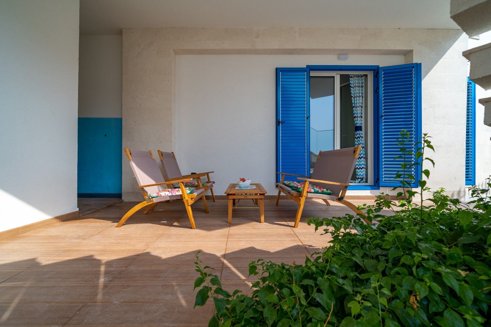 Cozy terrace with wooden furniture and blue shutters in a house in Blizikuće, Montenegro.