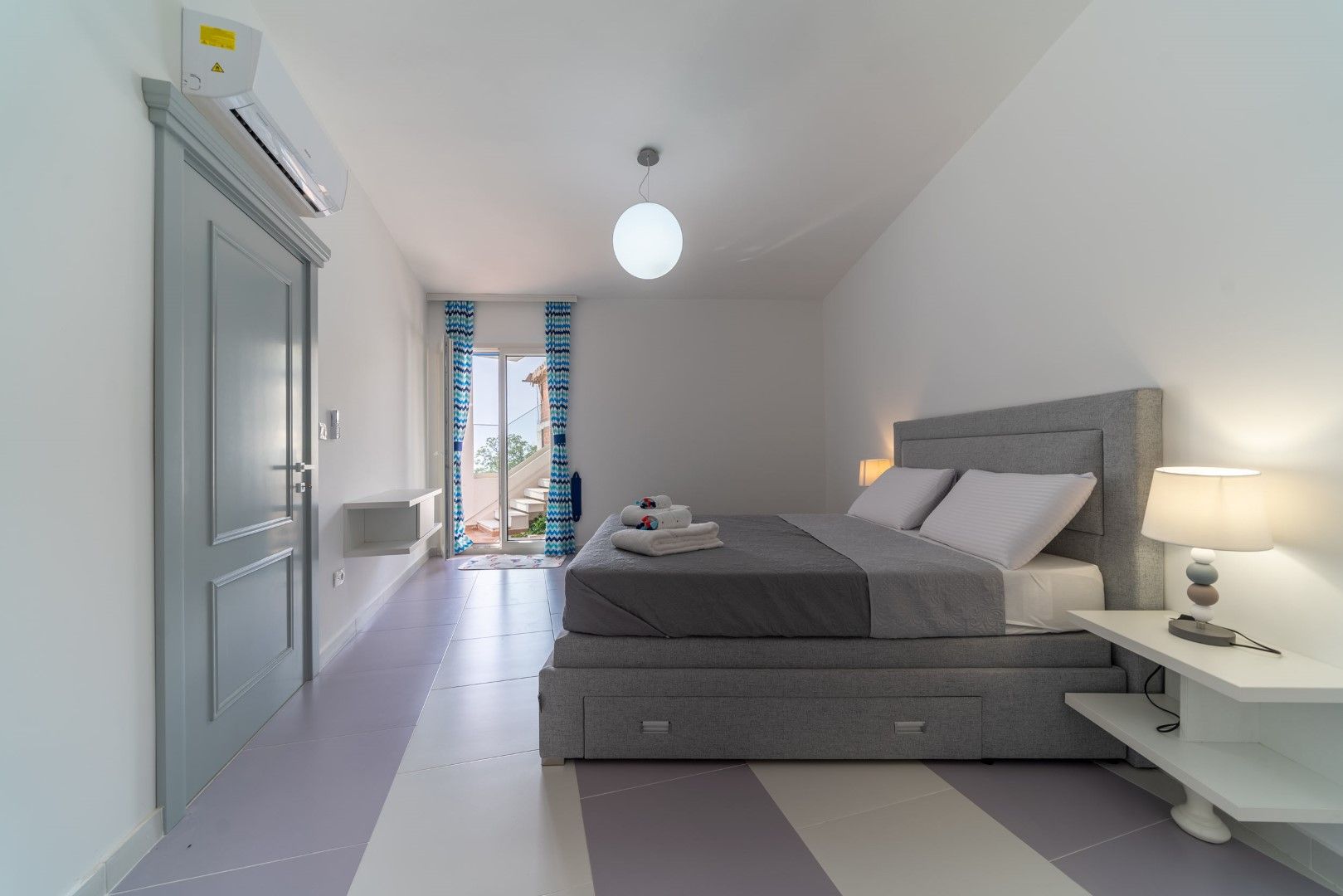 Modern bedroom with a gray bed in a house, Blizikuće, Montenegro: bright interior, access to the terrace, and air conditioning.