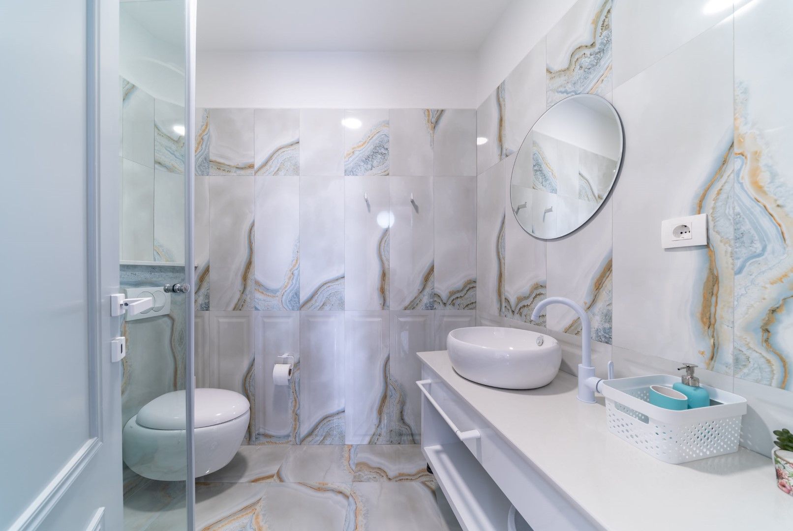 Modern bathroom in a house in Blizikuće, Montenegro: marble-look tiles, a vessel sink, and a round mirror.