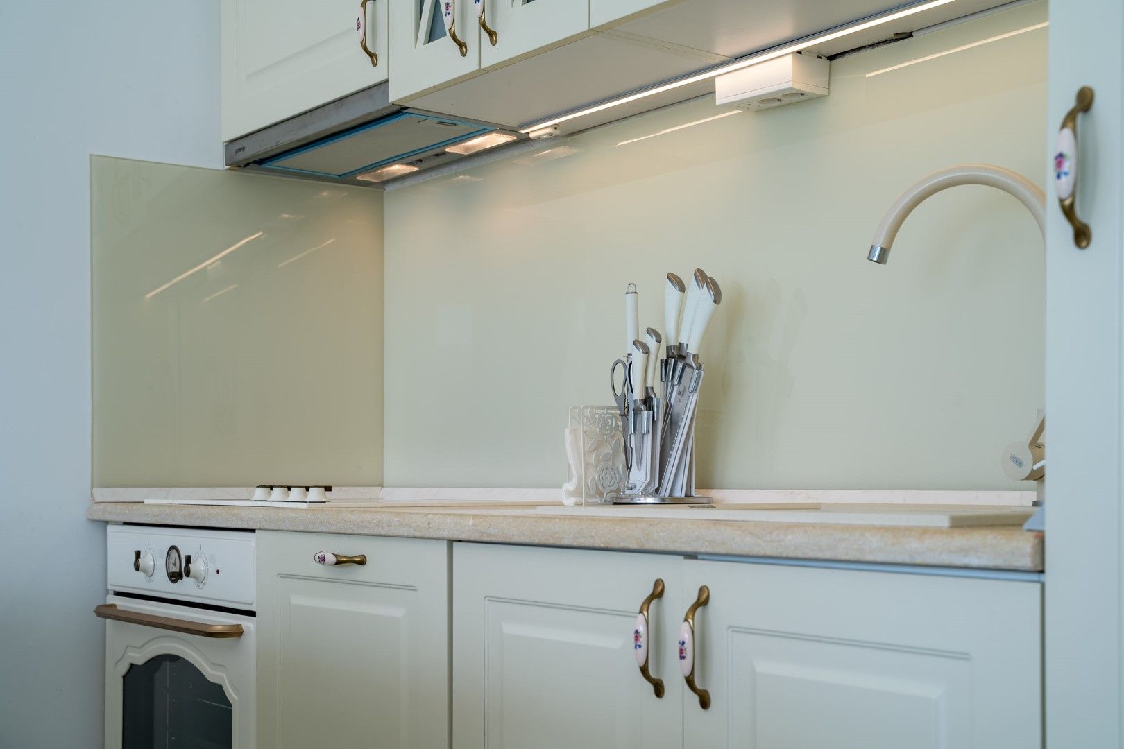 Bright classic-style kitchen in a house, Blizikuće, Montenegro: built-in appliances, backsplash, and knife set.