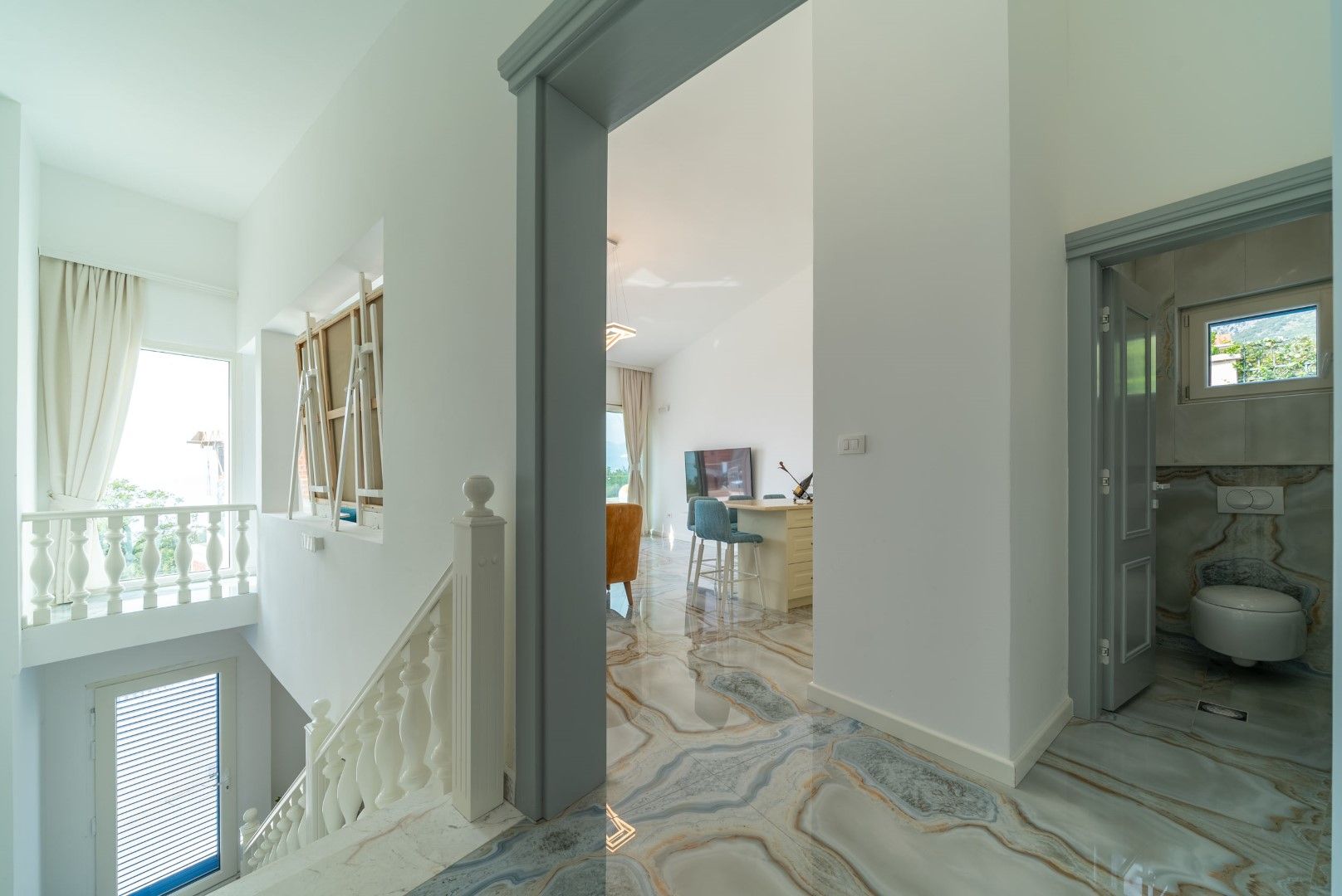 Interior of a house in Blizikuće, Montenegro: a bright hall with a marble floor, a staircase with a balustrade, and an entrance to the bathroom.