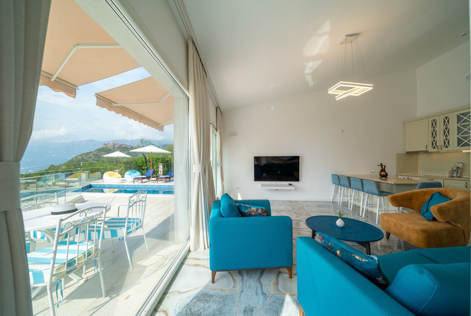 Living room with panoramic windows, a terrace, and a pool in the house, Blizikuće, Montenegro. Modern interior with bright furniture.