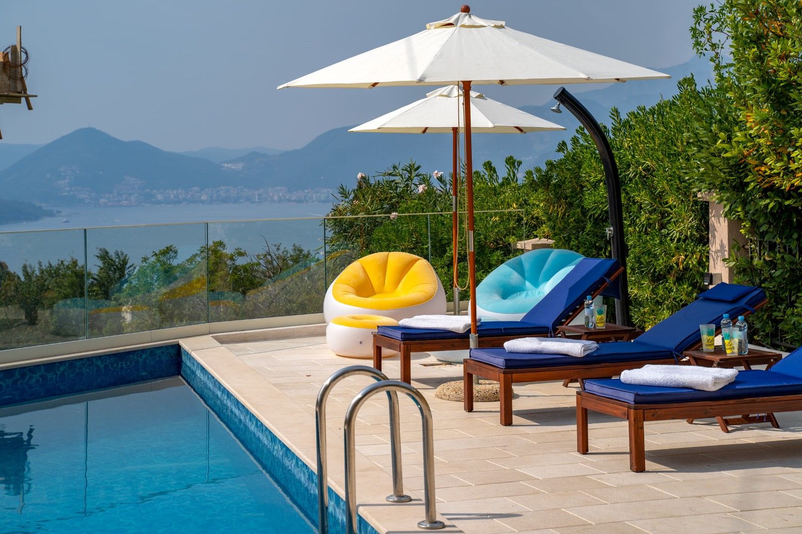 Pool with sea and mountain views at a house in Blizikuće, Montenegro: sun loungers, umbrellas, and a lounge area on the terrace.