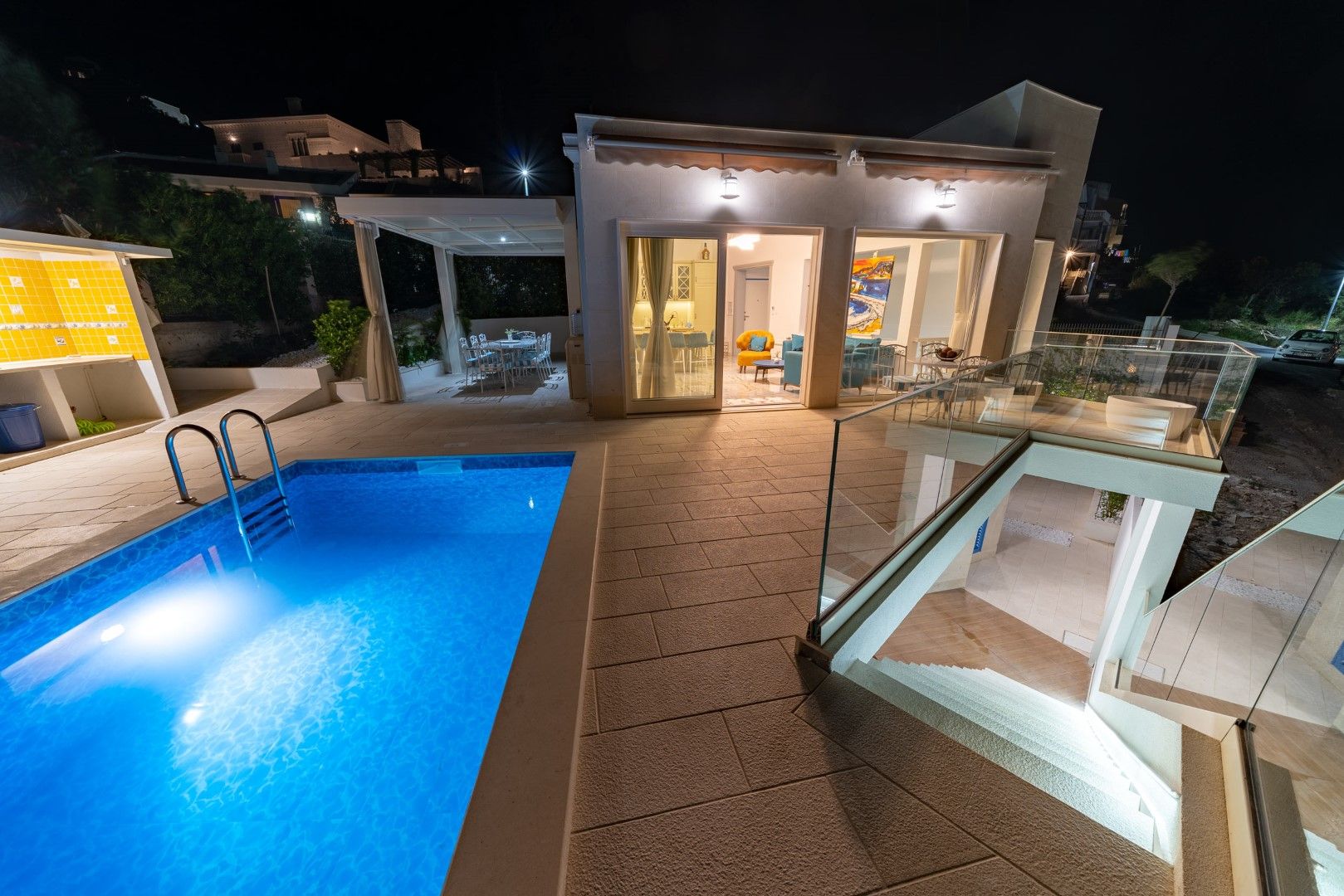 Modern villa with a pool and terrace in Blizikuće, Montenegro: night view of the house with lighting and a lounge area.